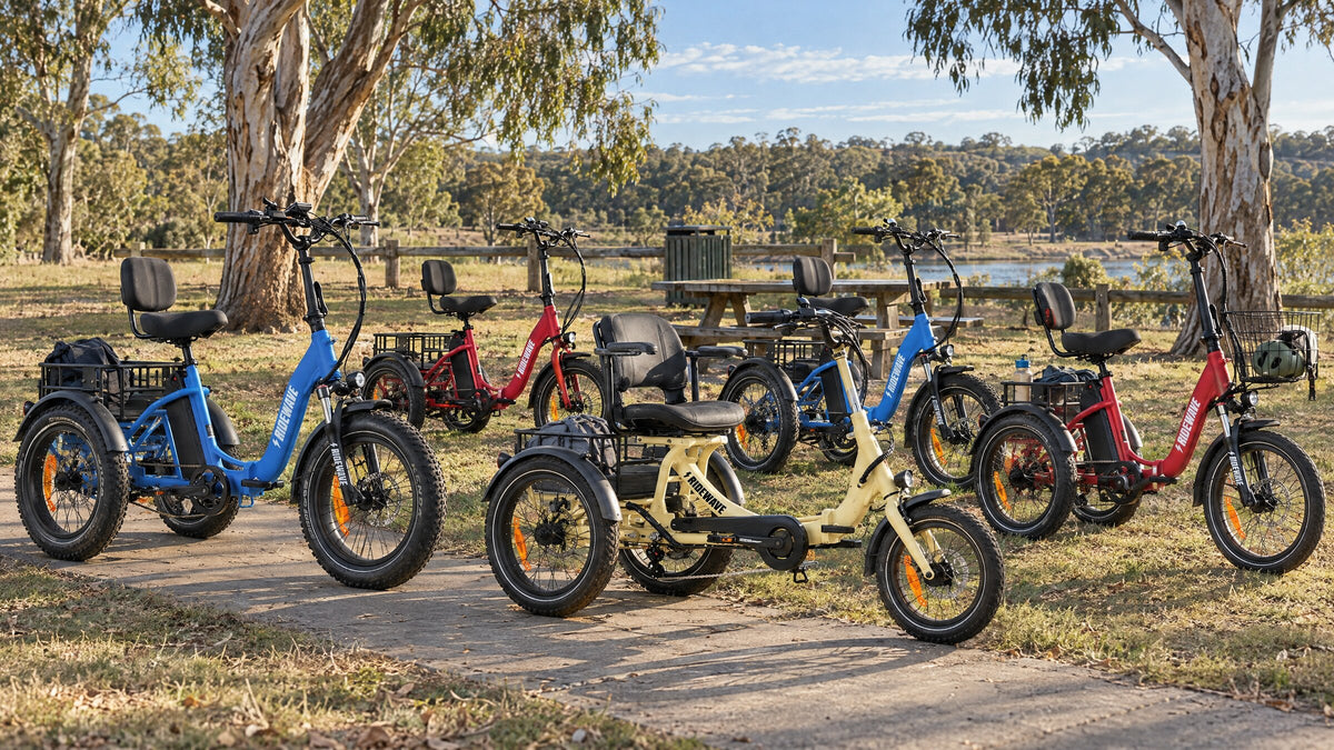 Ridewave electric trikes, among them a cream Platypus, a red Quokka and a blue Wallaby Plus, parked together at a park rest stop under gum trees